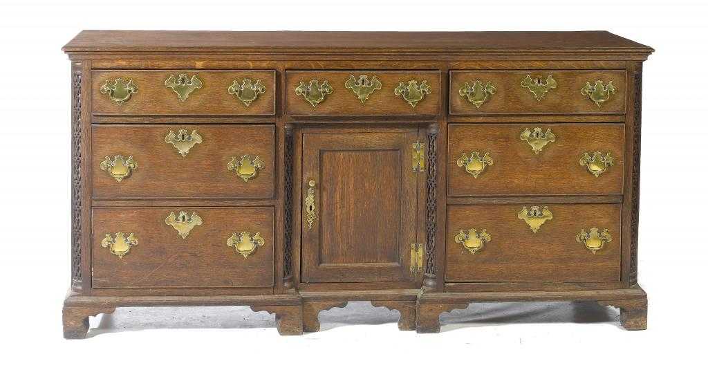 Appraisal: AN OAK DRESSER with seven drawers arranged around a slightly