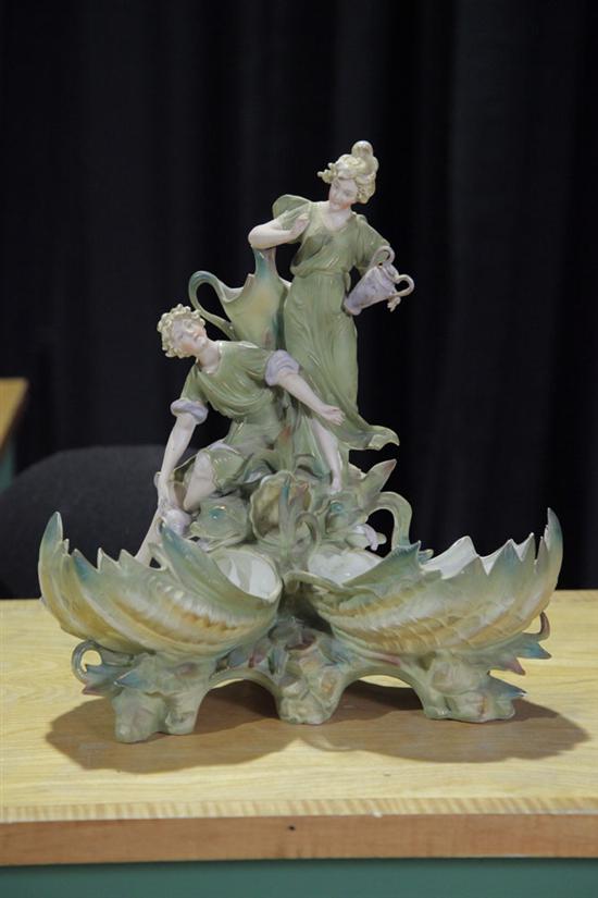 Appraisal: PORCELAIN FIGURAL CENTERPIECE Depicting a couple fetching water atop dolphin