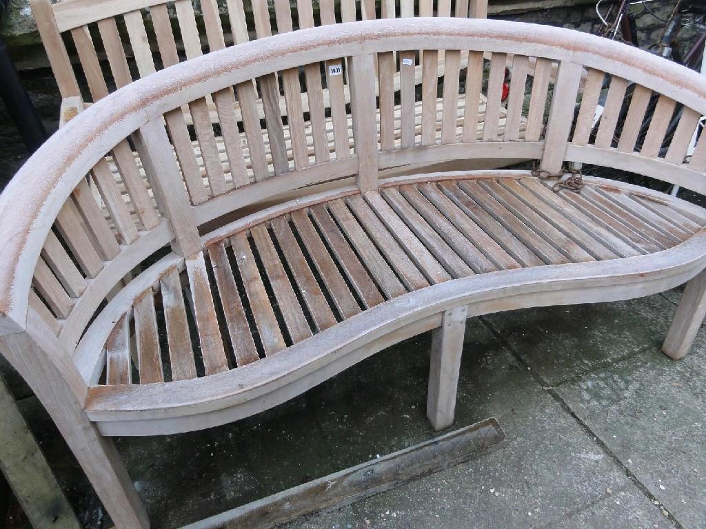 Appraisal: A contemporary teakwood garden bench of crescent shaped form with