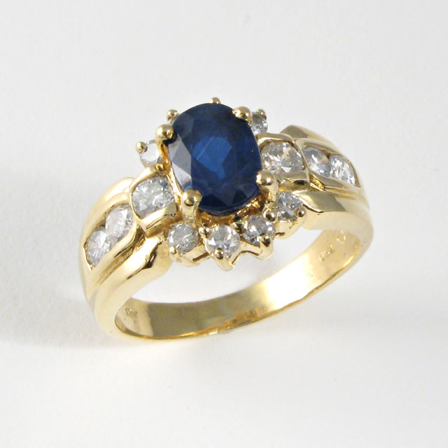 Appraisal: SAPPHIRE DIAMOND AND YELLOW GOLD RING centering an oval-cut blue