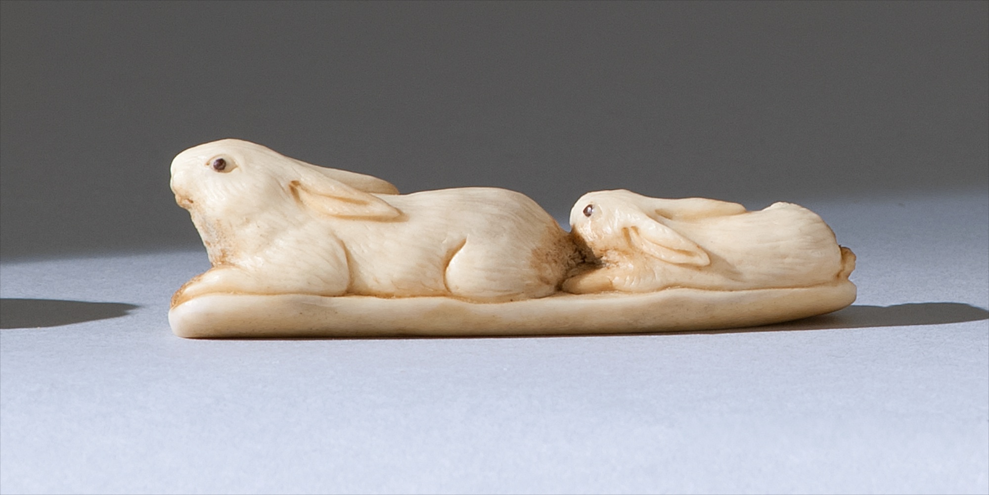 Appraisal: STAGHORN NETSUKE th CenturyBy Hakuo Depicting two rabbits with horn-inlaid