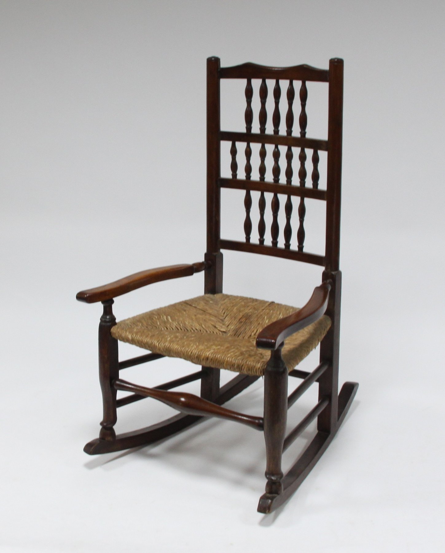 Appraisal: A spindle back rocking chair with rush seat