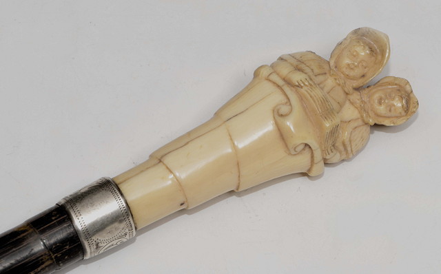 Appraisal: A VICTORIAN CARVED IVORY AND MALACCA PARASOL HANDLE decorated two