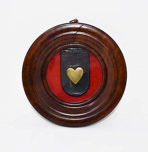 Appraisal: Brass heart on a leather strap framed Brass heart on