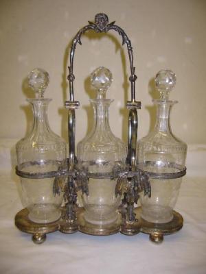 Appraisal: A TANTALUS the three cylindrical decanters with faceted spherical stoppers