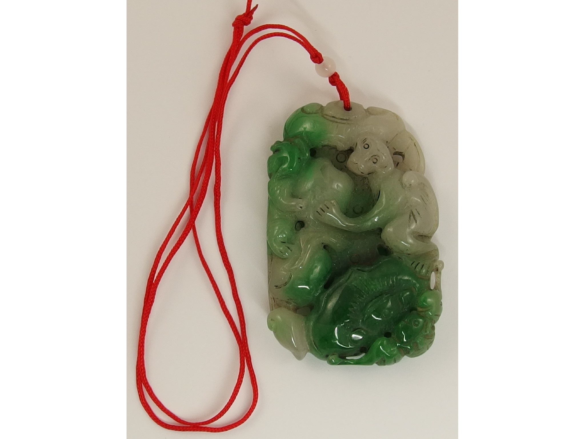 Appraisal: A Chinese green hard stone pendant carved with monkeys foo