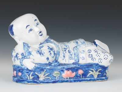 Appraisal: Recumbent Porcelain Child Figure Blue and white glazed porcelain figure