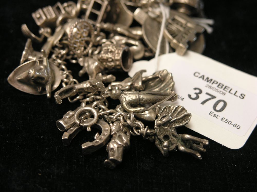 Appraisal: A silver charm bracelet approx twenty-five charms approx ozs gross