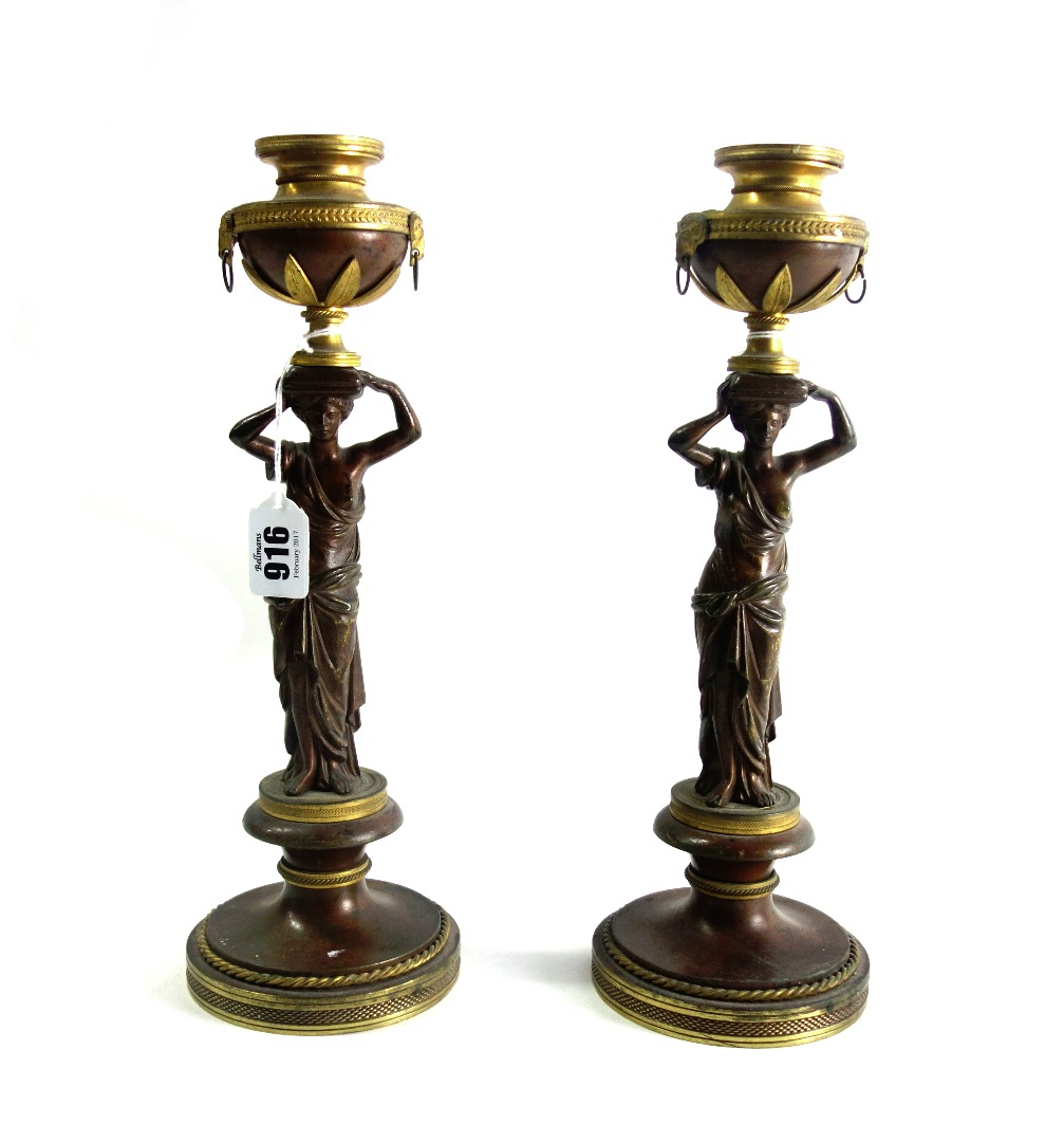 Appraisal: A pair of patinated and gilt bronze figural candlesticks th