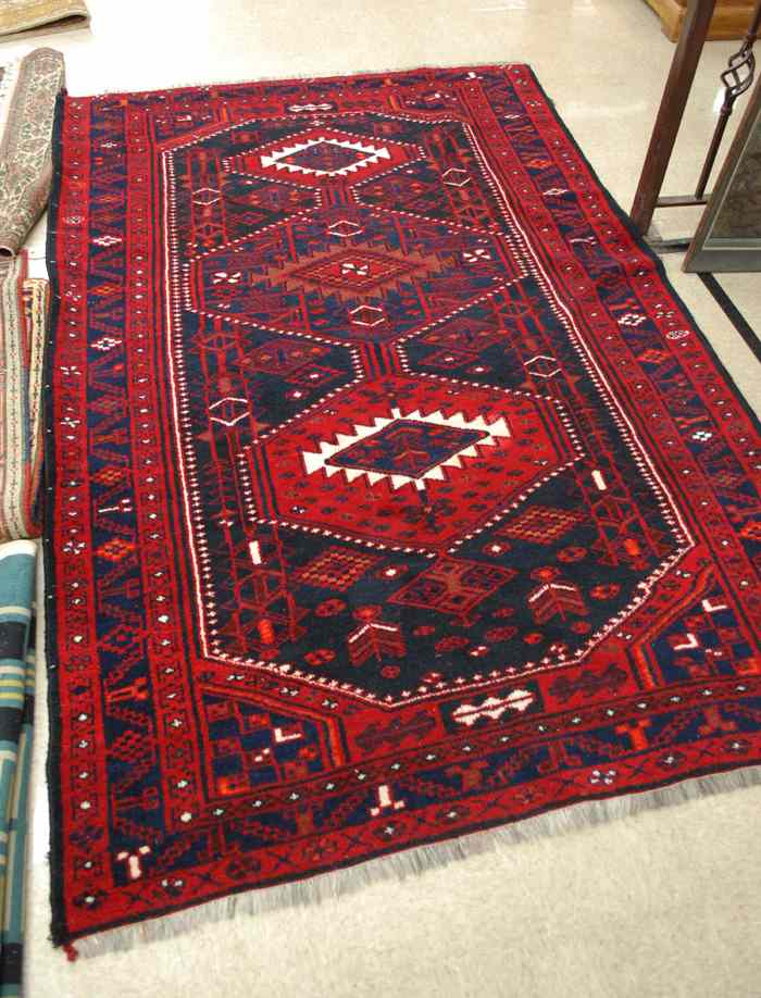 Appraisal: AN AFGHAN BELOUCH CARPET featuring three geometric medallions hand knotted