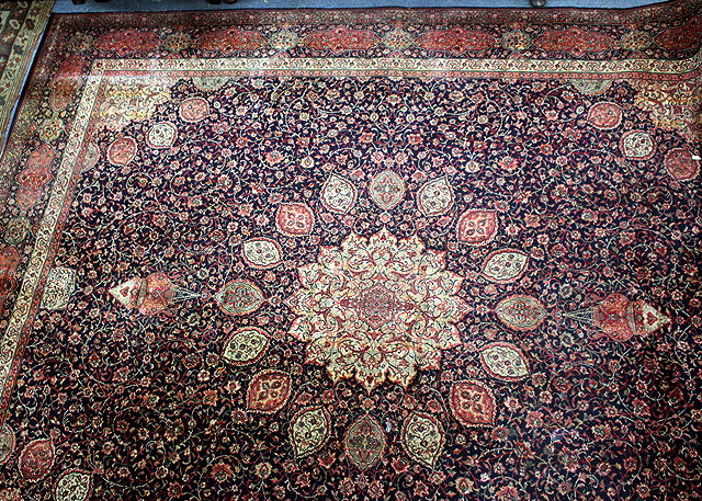 Appraisal: A LARGE MACHINE MADE RED GROUND RUG