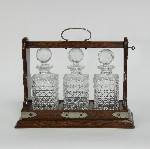 Appraisal: An oak tantalus fitted three square cut glass decanters and