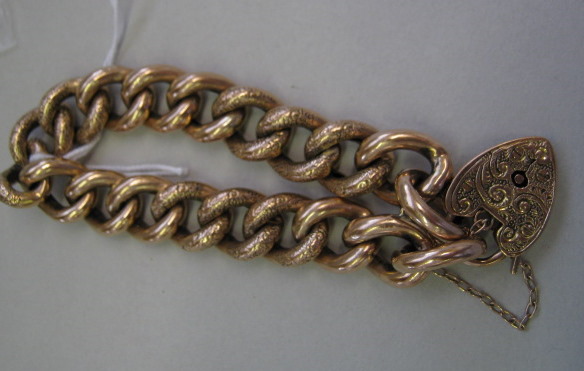 Appraisal: A gold decorated and plain curb link bracelet on a