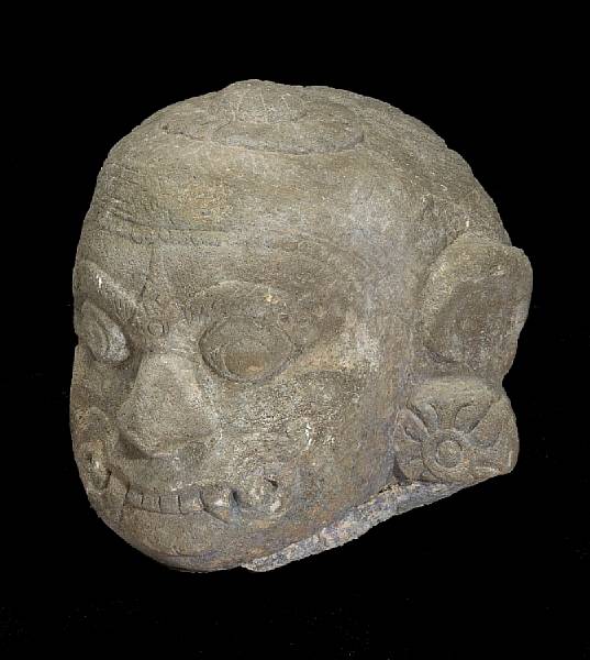 Appraisal: A Southeast Asian carved stone head of a ferocious deity