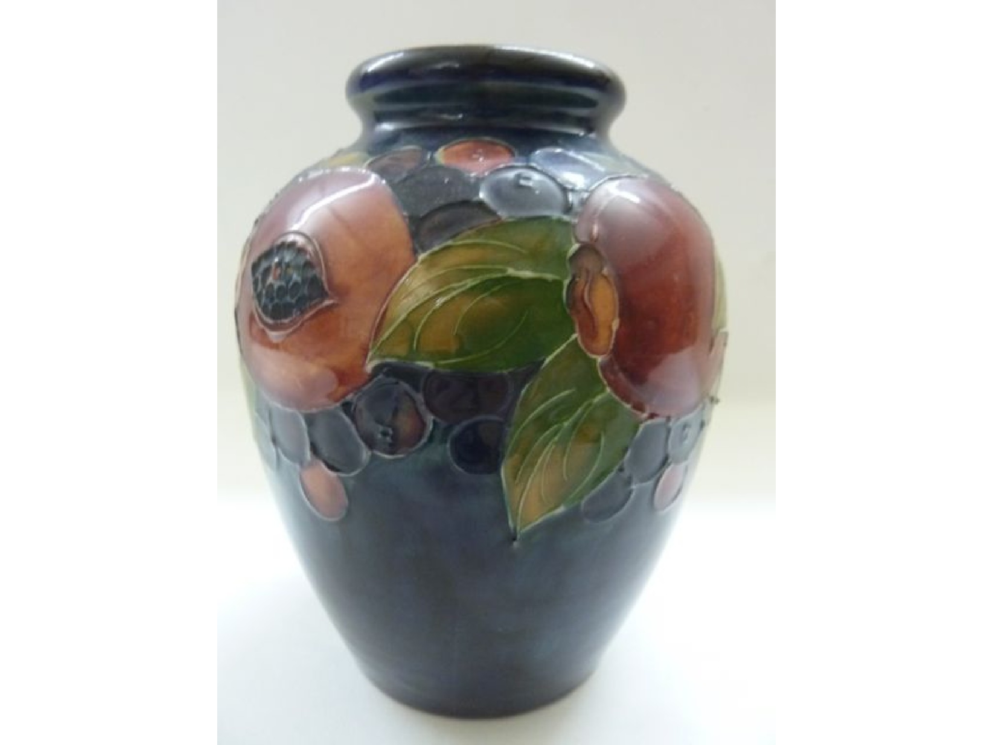 Appraisal: A Moorcroft dark blue ground vase with painted pomegranate and