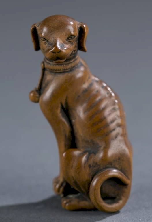 Appraisal: Japanese netsuke of a seated dog Tomotada A Japanese wood