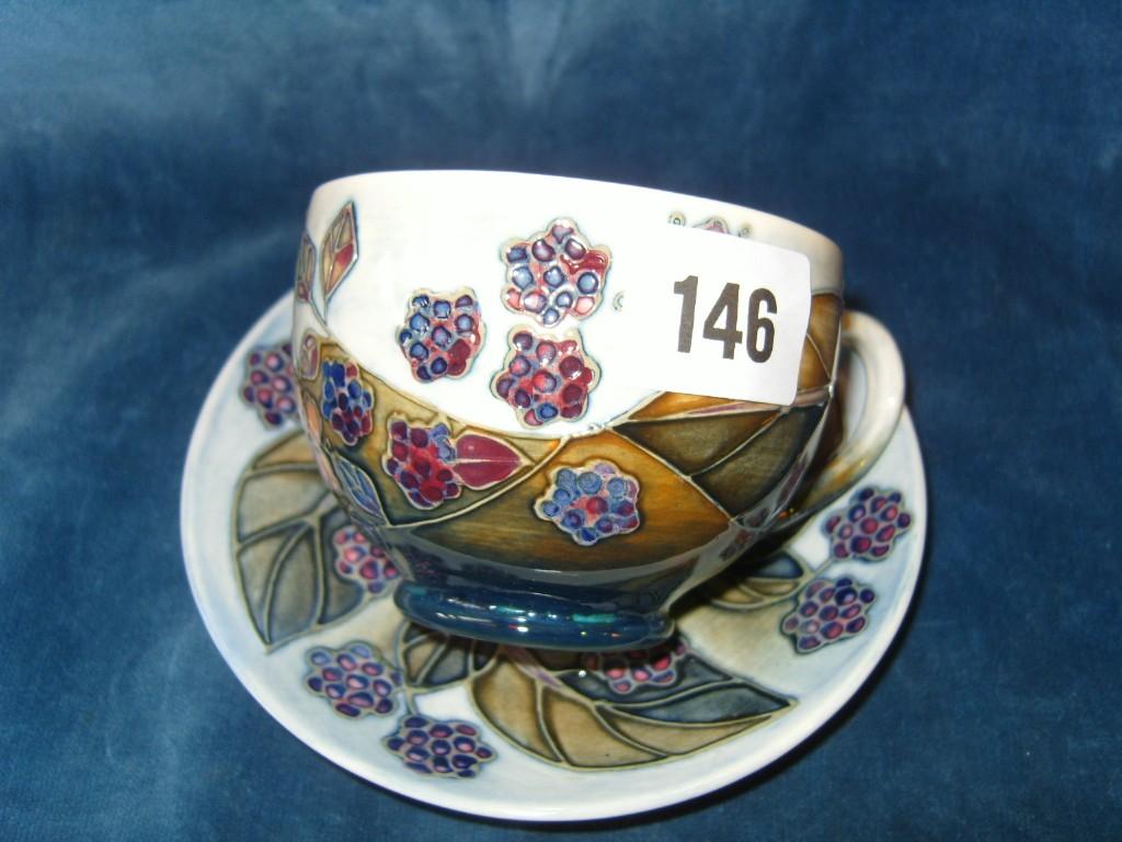 Appraisal: A Moorcroft teacup and saucer with painted and raised bramble