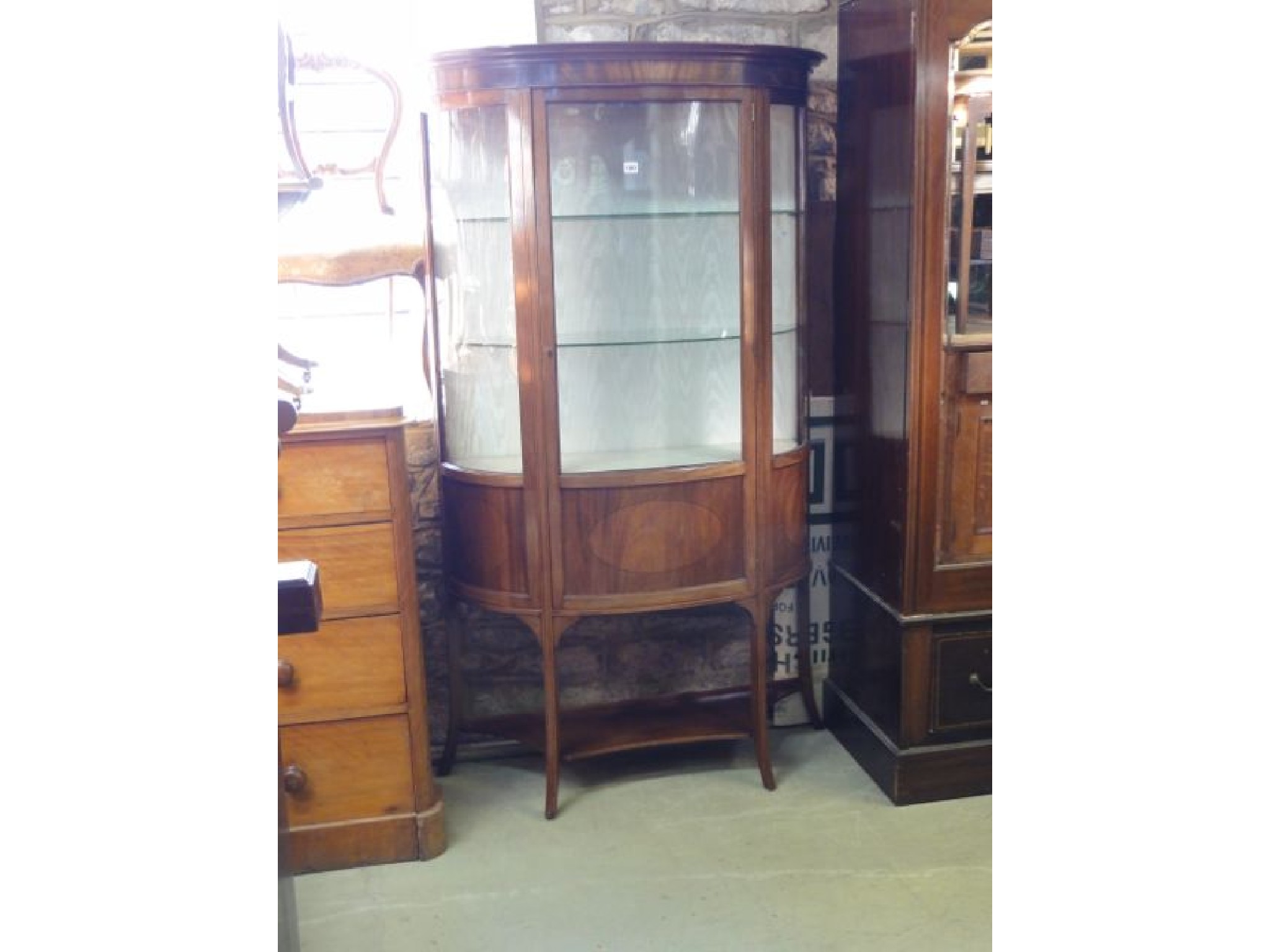 Appraisal: An inlaid Edwardian mahogany freestanding demi-lune display cabinet enclosed by