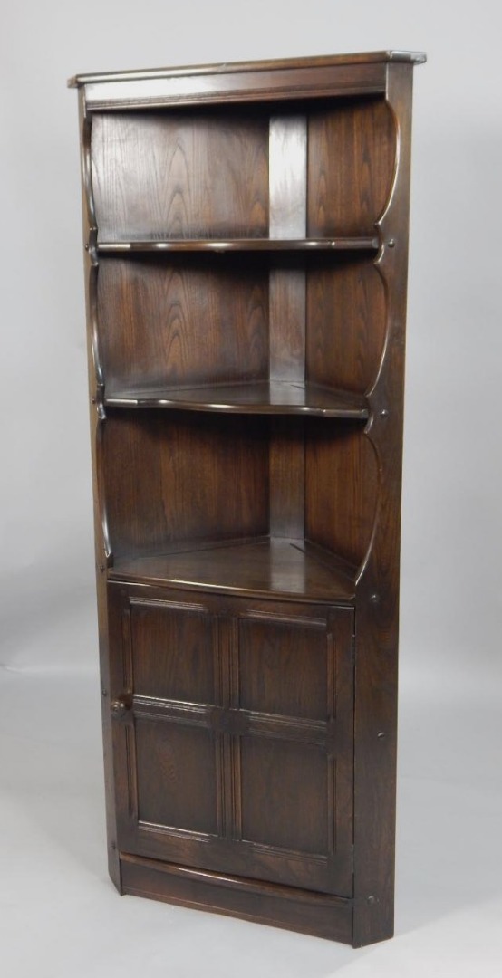 Appraisal: An Ercol stained elm corner cabinet with two plate shelves