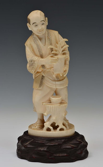 Appraisal: A JAPANESE IVORY OKIMONO of a standing bonsai gardener holding