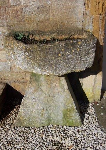 Appraisal: An irregular D shaped stone trough on a tapered stone