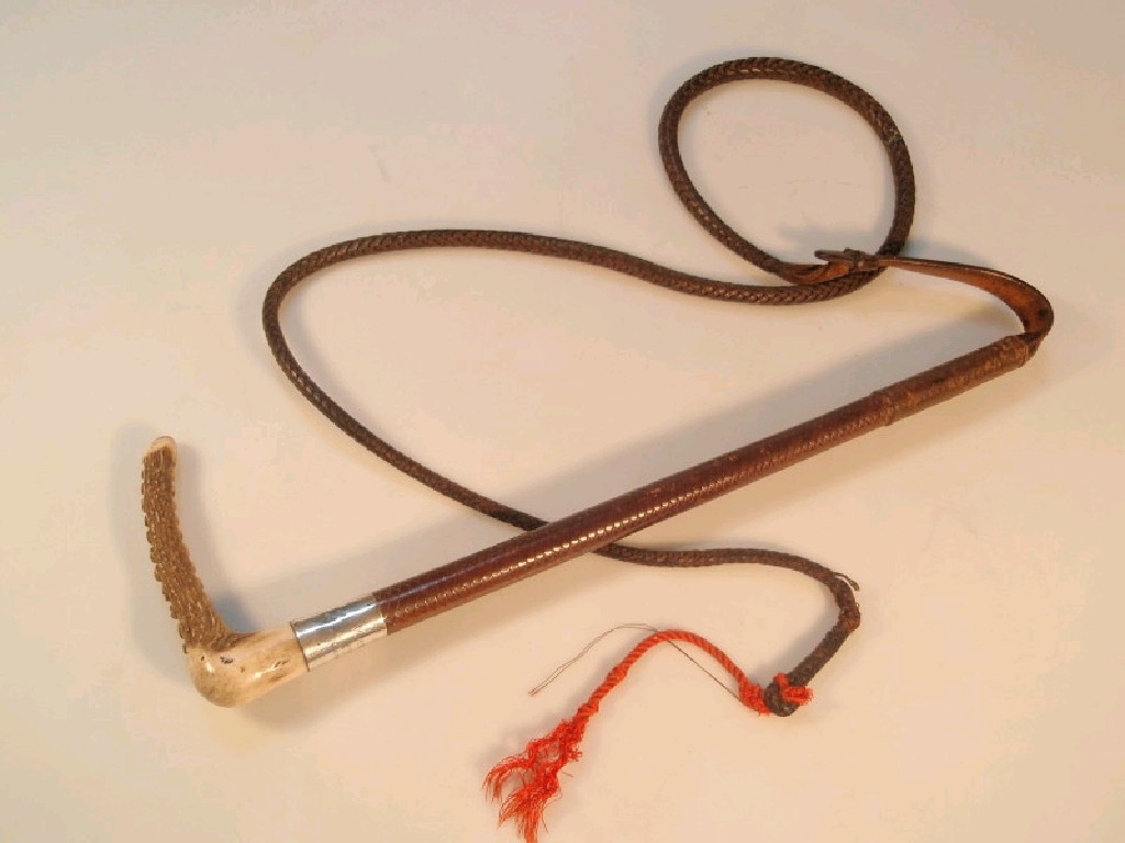 Appraisal: A plaited leather hunting whip with a horn handle mounted