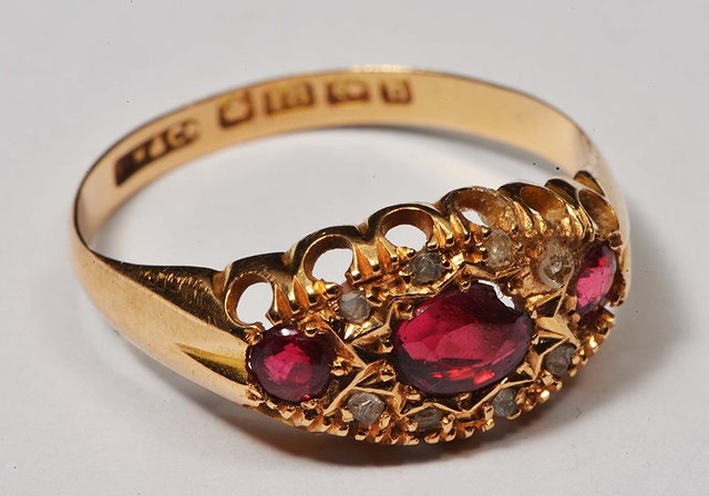 Appraisal: AN CT GOLD RING with stylised ruby and diamond chip