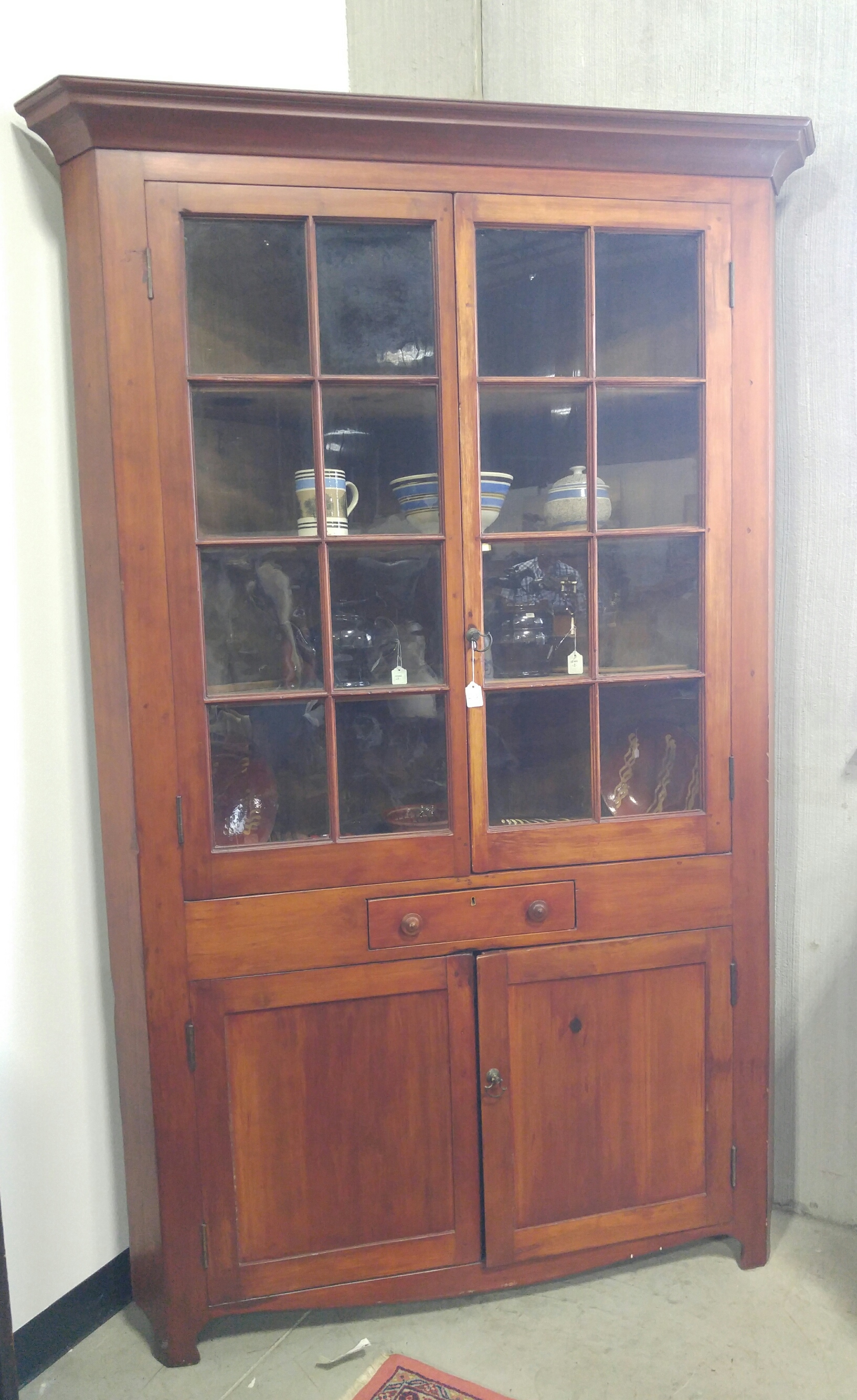 Appraisal: ONE-PIECE SIXTEEN-PANE CORNER CUPBOARD American mid th century cherry with