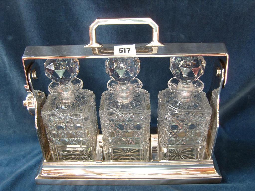 Appraisal: A silver plated Tantalus fitted with three cut glass decanters