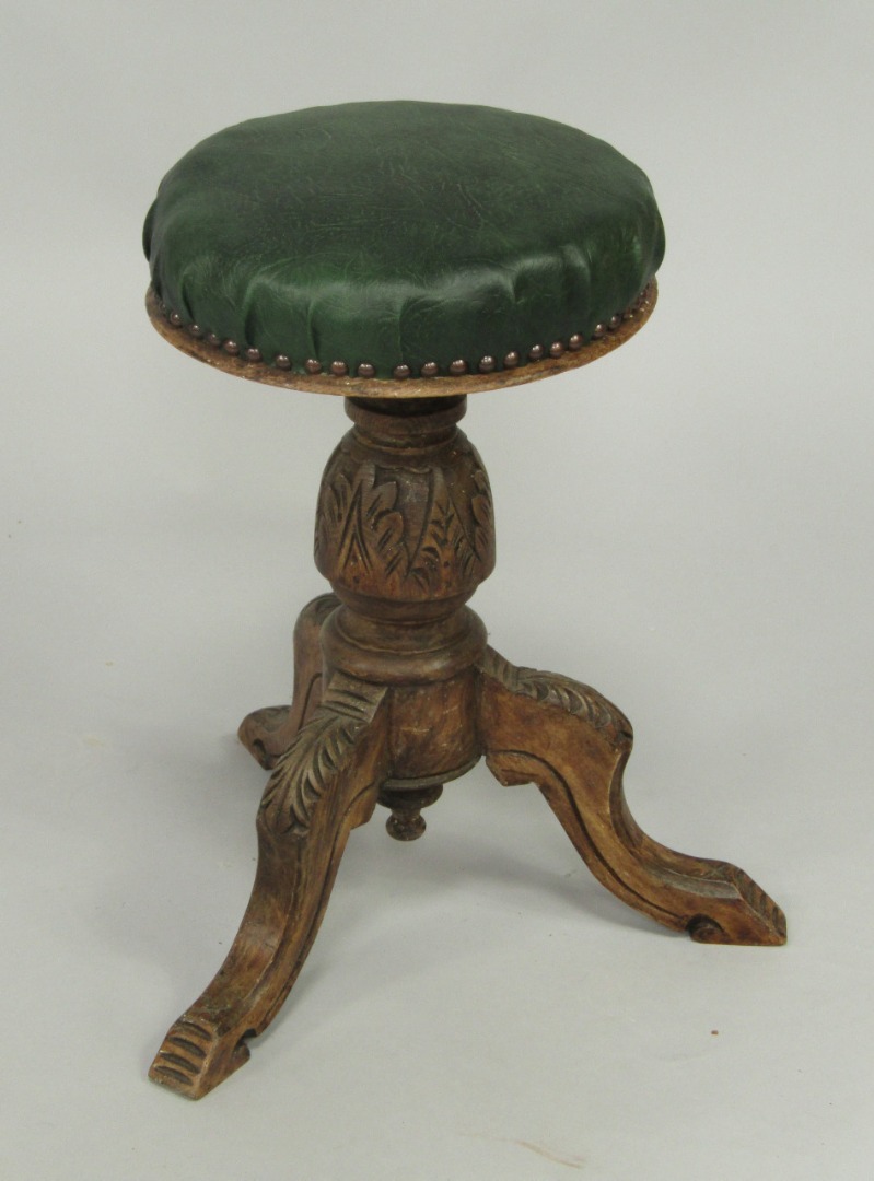 Appraisal: A Victorian carved oak piano stool with a revolving overstuffed