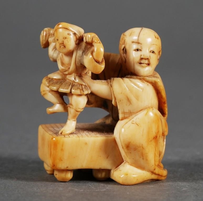 Appraisal: Carved Japanese ivory netsuke figure of a puppeteer Signed on