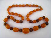 Appraisal: An amber and carved wood bead necklace largest bead approx