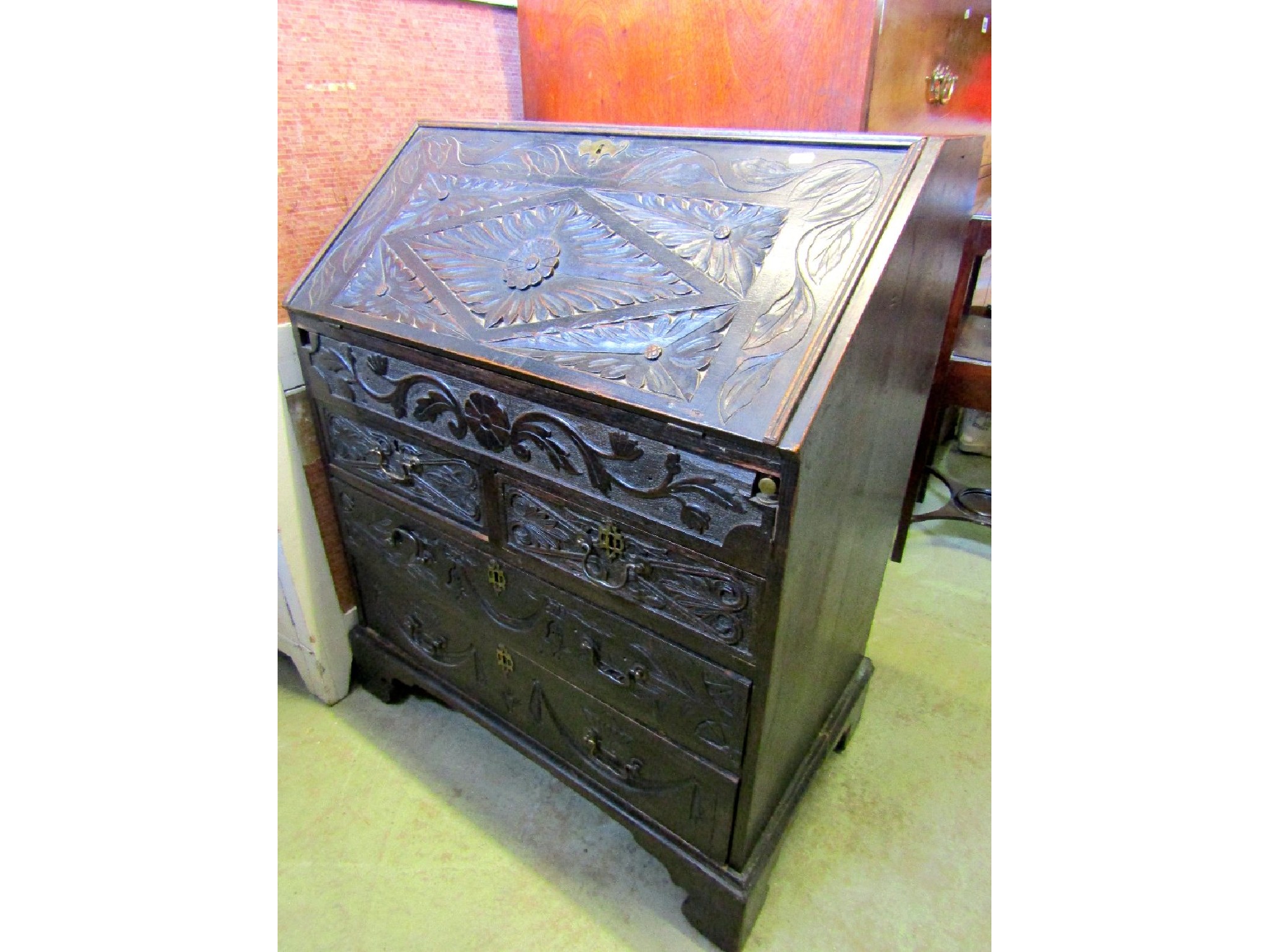 Appraisal: A small Victorianised oak bureau the front elevation with carved