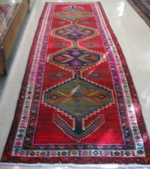 Appraisal: PERSIAN AZAR RUNNER centering a row of three colorful geometric