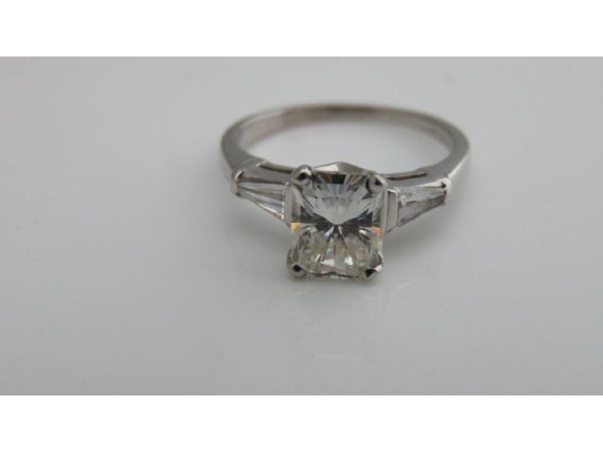 Appraisal: A diamond ring centred with a claw-set radiant-cut diamond weighing