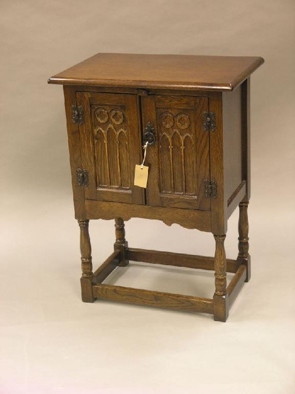 Appraisal: A reproduction dark oak side cupboard enclosed by a pair