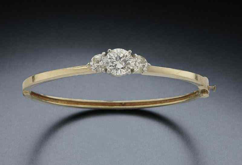 Appraisal: K gold and diamond bangle bracelet the central round brilliant