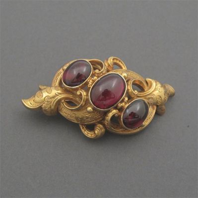 Appraisal: A Victorian gold scroll brooch set with three cabochon garnets