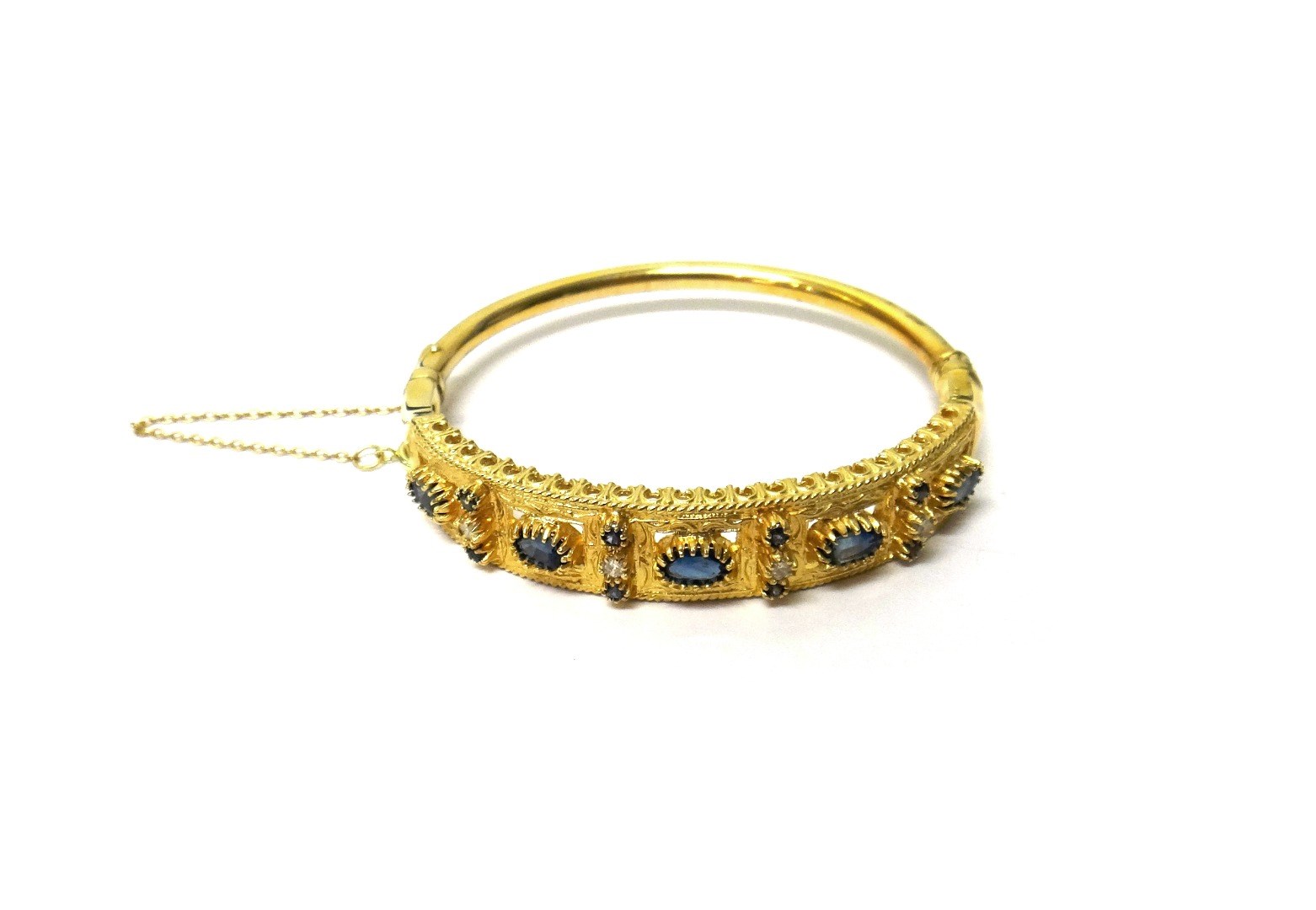 Appraisal: A gold sapphire and diamond set oval hinged bangle the