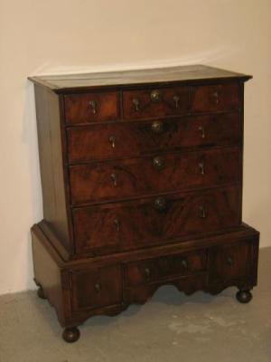 Appraisal: A WALNUT CHEST ON STAND with feather banding moulded cornice