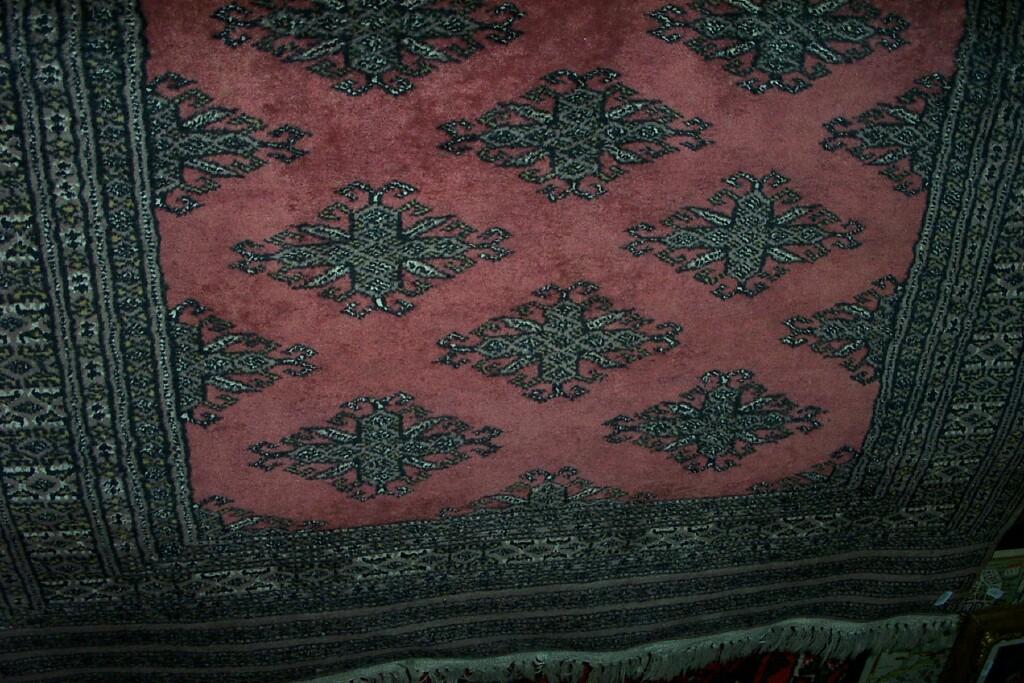 Appraisal: A pink ground Eastern wool rug with repeating hooked motifs