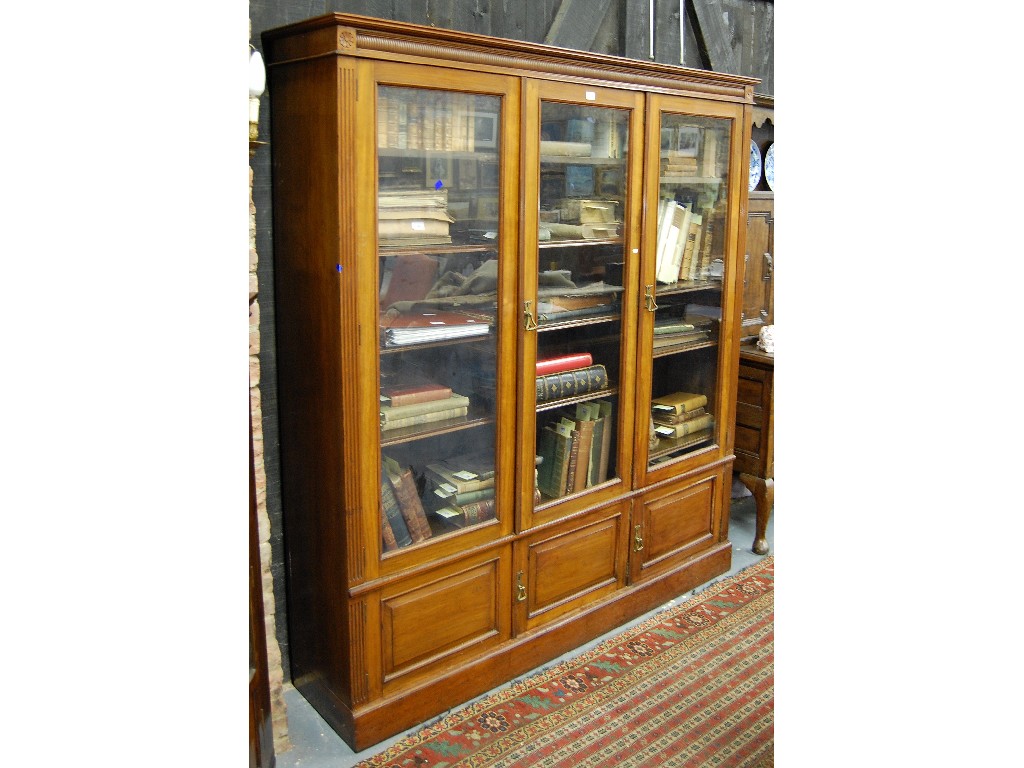 Appraisal: An Edwardian walnut bookcase with three glazed doors enclosing adjustable