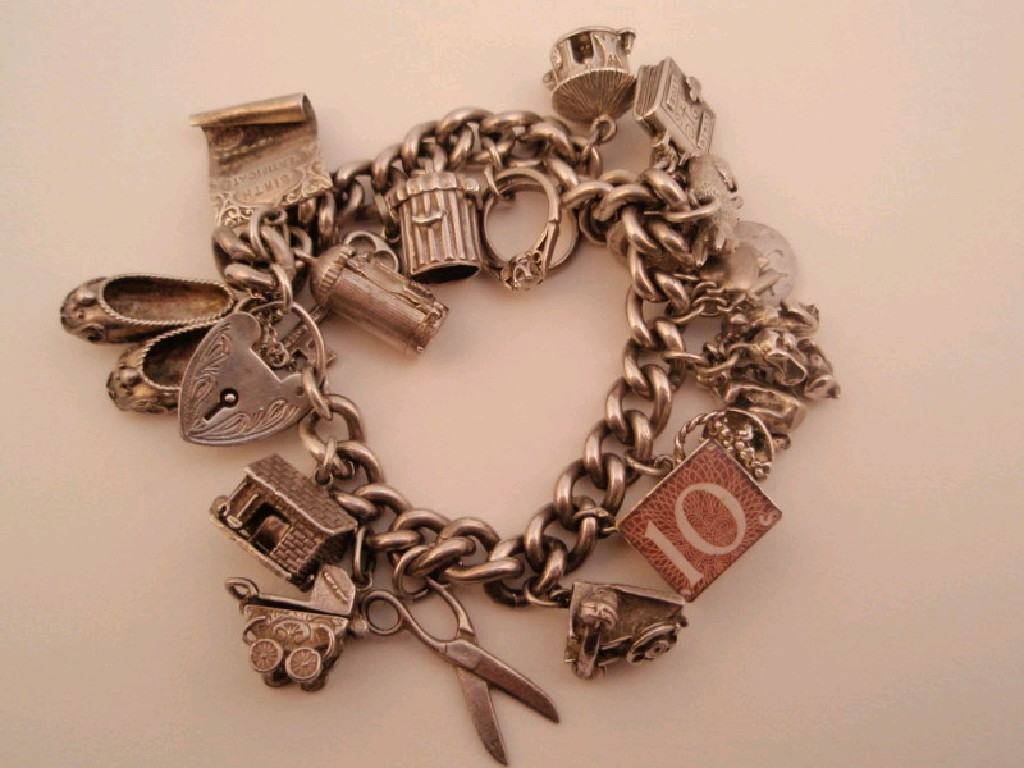 Appraisal: A silver curb link charm bracelet nineteen attached charms g