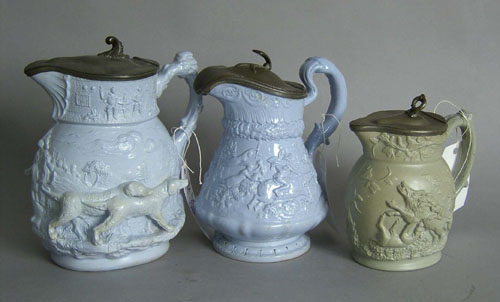 Appraisal: Three relief decorated pottery pitchers ca with pewter lids h