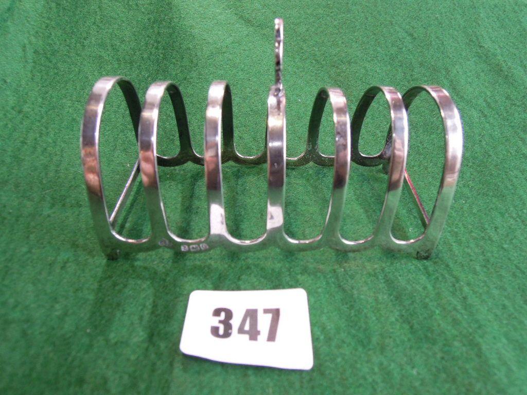 Appraisal: A silver toast rack with club shaped loop handle Birmingham