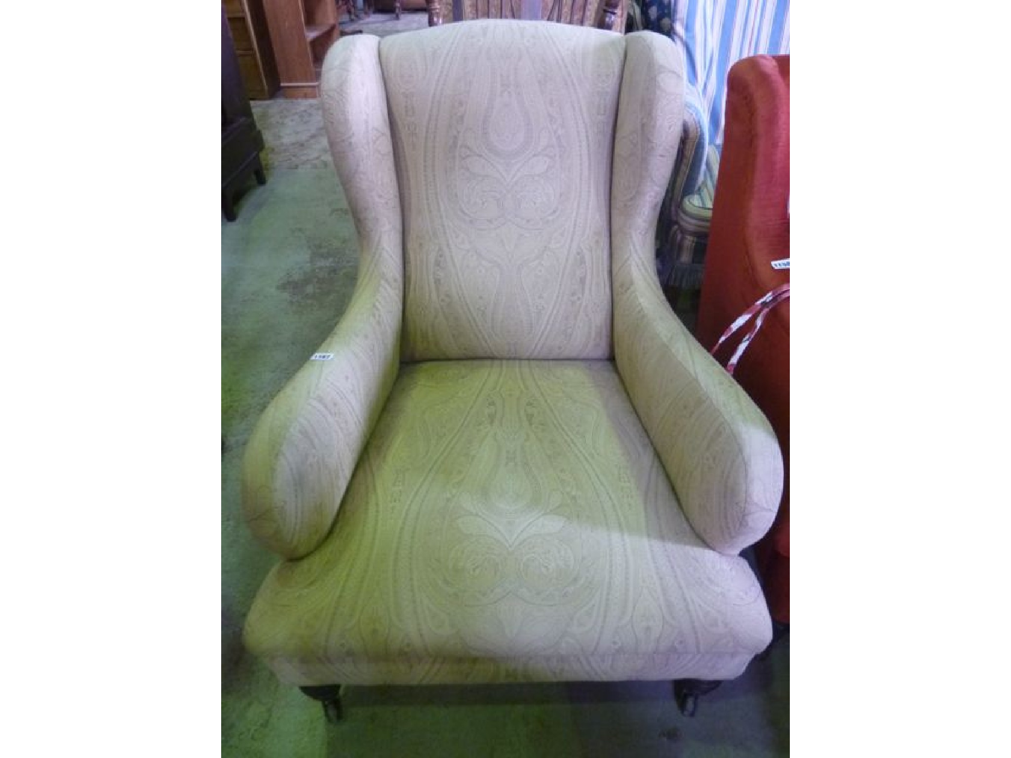 Appraisal: An Edwardian low shallow wing back armchair of shaped outline