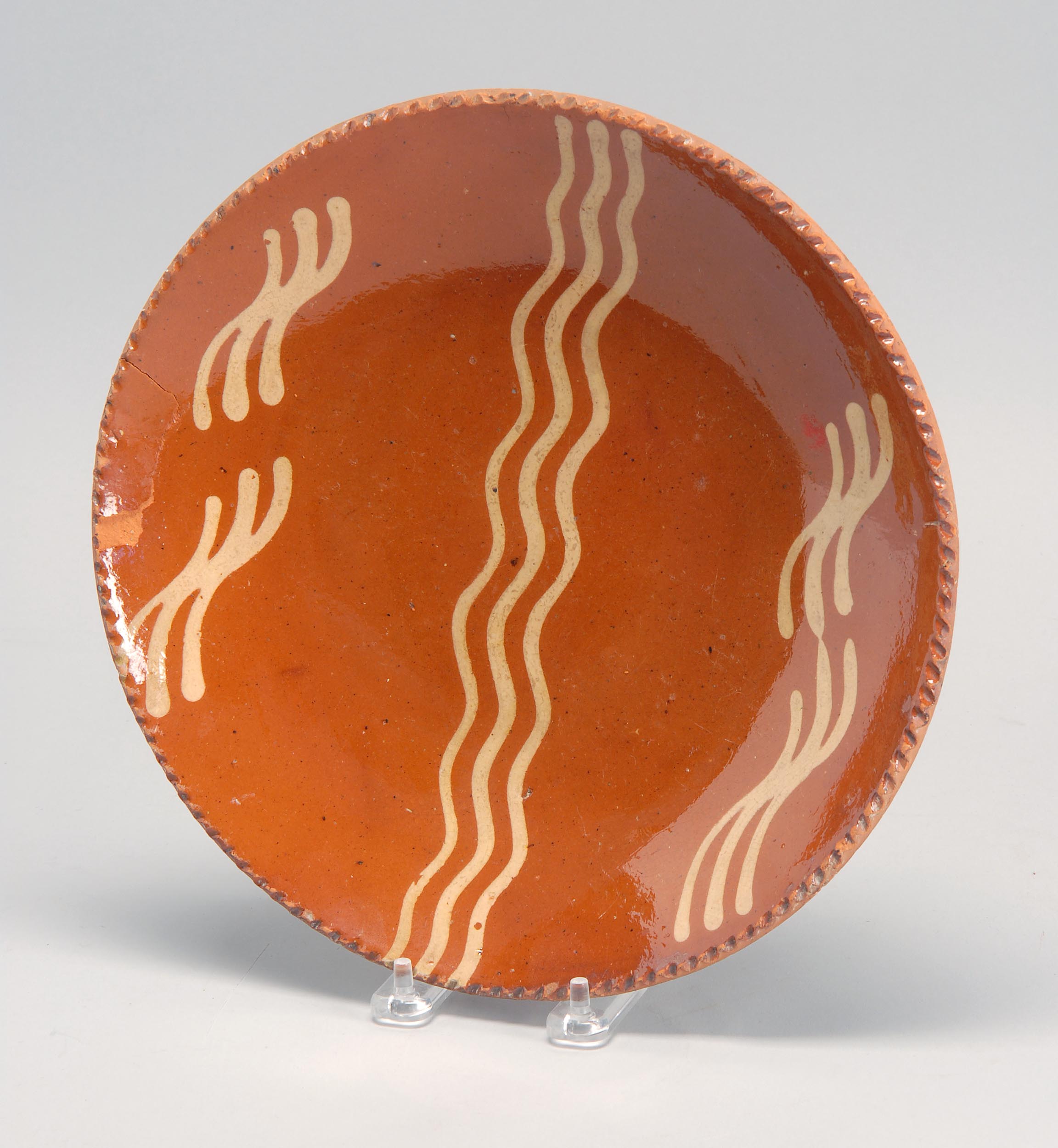 Appraisal: SLIP-DECORATED REDWARE PLATE with wave design and piecrust rim Diameter