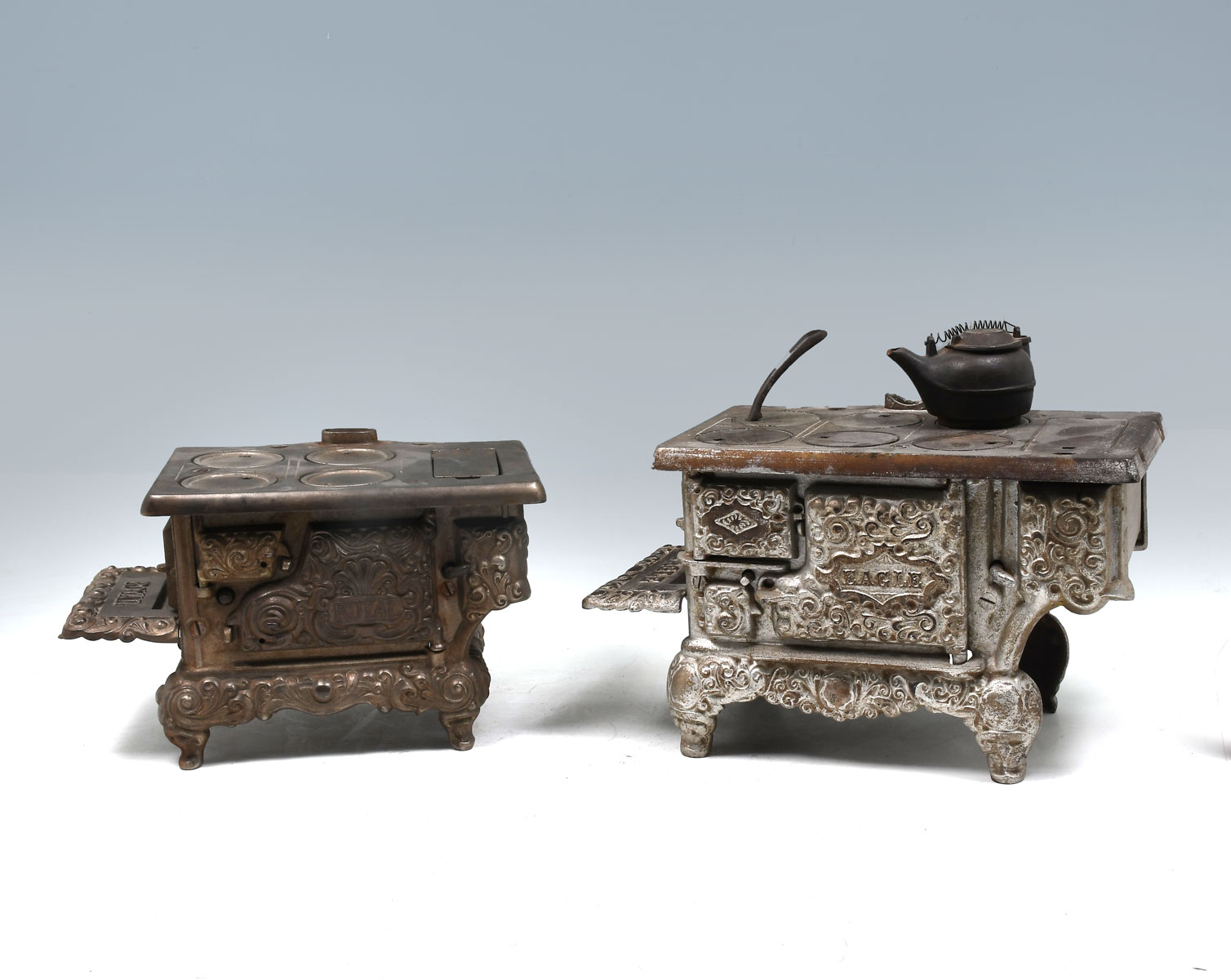 Appraisal: TWO CAST IRON MINIATURE STOVES - Silver painted Eagle a