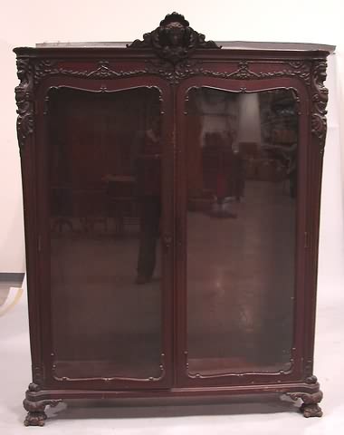 Appraisal: Mahogany two door glass front bookcase with figural carved pediment