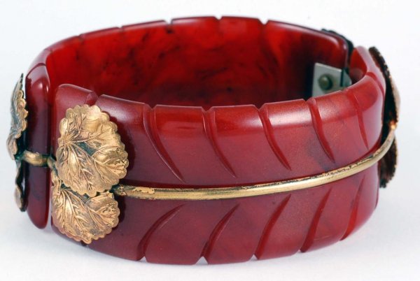 Appraisal: A carved Bakelite hinged cuff bracelet in an orange brown